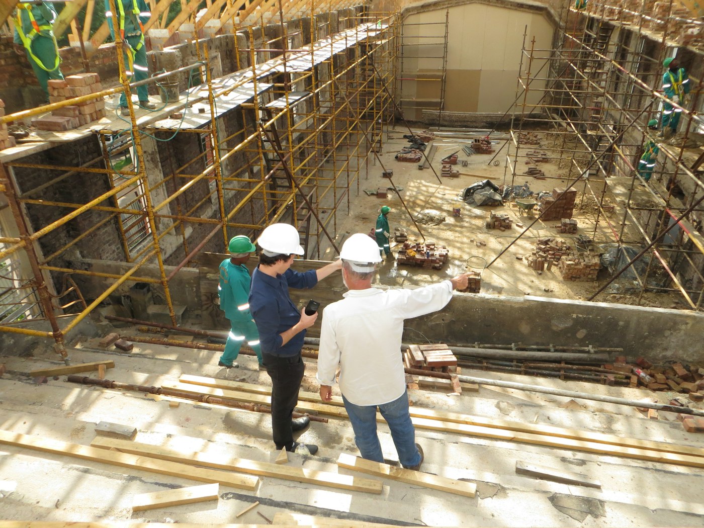 Two site managers in hard hats reviewing progress on a building under construction