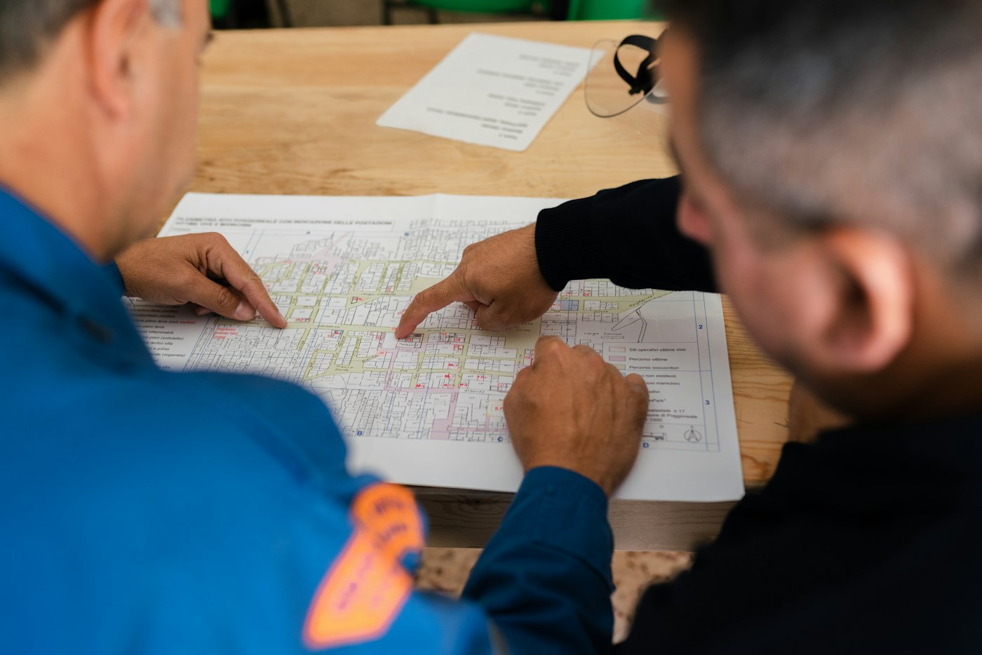 Two people in work uniforms reviewing a printed map on a table
