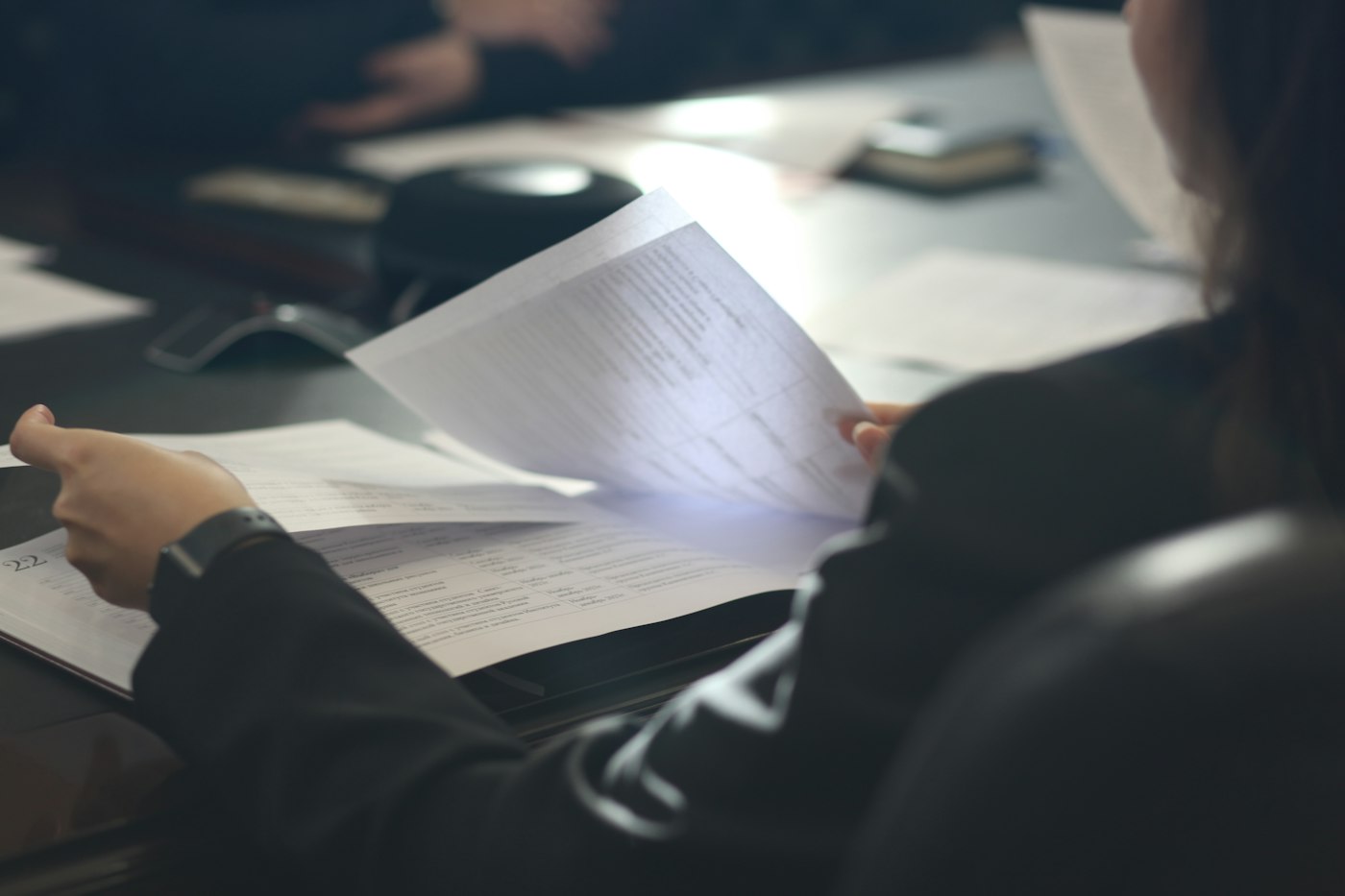 Professional at a meeting table reading a document